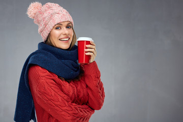 Smiling woman wearing warm clothes with winter hat holding red c