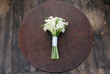 A wedding bouquet of white flowers lies on a round table