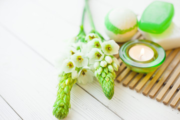 Aromatherapy spa concept with soap bars, ball of sea salt, flowers and candle on wooden bars carpet, closup