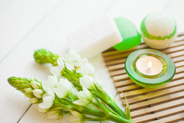 Aromatherapy spa concept with soap bars, ball of sea salt, flowers and candle on wooden bars carpet, closup