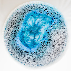 detail of detergent dissolving in water with foam and bubbles
