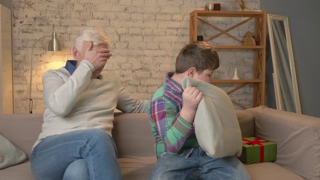 Grandson gives his Grandfather a gift. a fat child gives a gift to An elderly man, Joy, surprise, happiness, emotion, feeling, impulsively, present. Home comfort, family idyll, cosiness concept