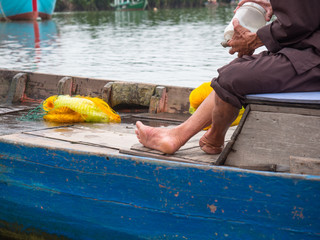 Vietnamese fisherman in traditional clothes closeup sitting in a wooden boat without a foot on the left leg