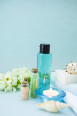 Obraz na płótnie Canvas Aromatherapy spa concept with essential oil in blue glass bottle, soap bars, candle, towel, flowers and sea shells on blue background, instagram