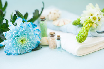 Aromatherapy spa concept with essential oil in blue glass bottle, sea salt, soap bar, towel, flowers and sea shells on blue background, instagram