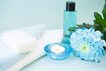 Obraz na płótnie Canvas Aromatherapy spa concept with essential oil in blue glass bottle, towel, candle, flowers on blue background, instagram