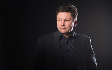 Portrait of a middle aged business man on a dark background.