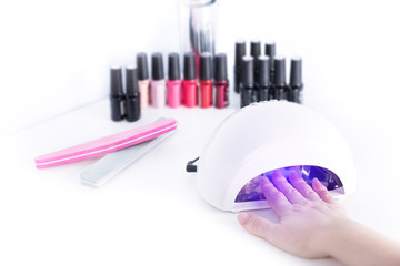 Woman drying neils in Led Lamp on white table