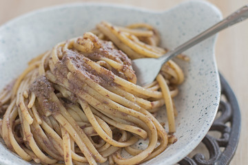 Linguine with taggiasca olives patè. Close up with a fork and an iron trivet.
