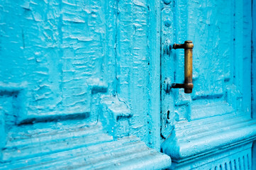 Close-up keyholes with curtains and a handle on the blue many times painted cracked double-barreled wooden vintage door of the last century with a post slit.