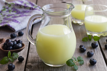 A jug of whey with blueberries in the background