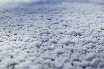 White fluffy snow sparkles under the rays of the first morning of the spring sun.