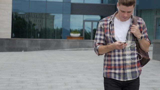 Candid student listens to music while searching something in phone