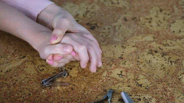 Mum is cutting hangnail to her son by Clippers on wood backgound and file him nails. Close-up hands