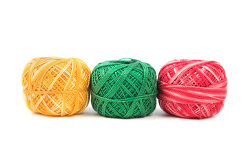Three colored sewing threads in a row on a white background. Blue, green and yellow threads