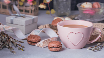 Pink coffee mug with sweet pastel french macaroons, gift box and pussy willow