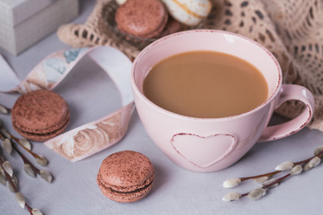 Pink coffee mug with sweet pastel french macaroons, gift box and pussy willow