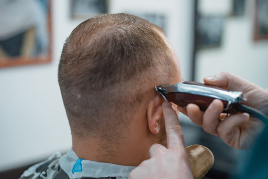 Man gets a cool haircut in barbershop. Barber cuts machine.