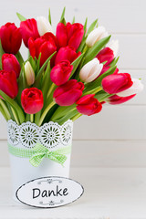 Fresh red tulip flowers bouquet on shelf in front of wooden wall.