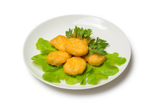 Chicken nagets with lettuce on a plate on a white background