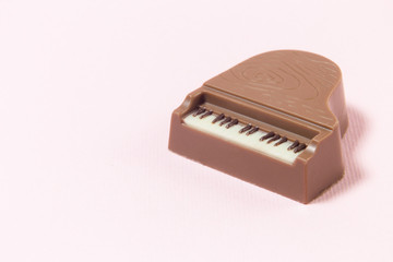 Miniature chocolate bar piano on pink background. Space for copy.