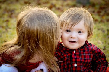 Fototapeta premium Two adorable small children outside in red holiday attire 