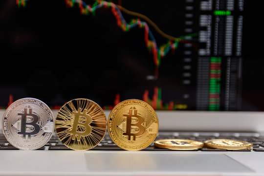 golden bitcoin on keyboard with chart on monitor