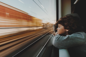 Close-up of a young Boy leaning on a window sill Looking Through a Train Window