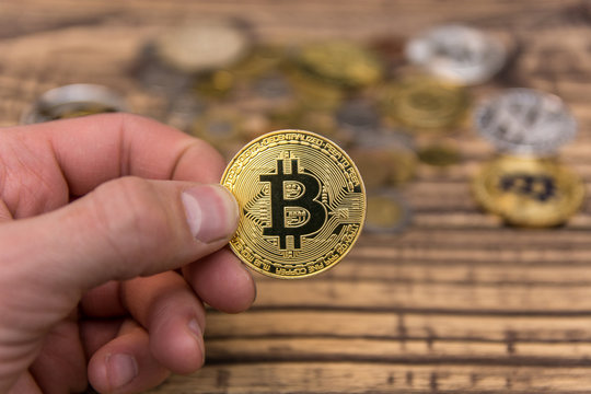  bitcoin holding in man&rsquo;s fingers on old wooden background
