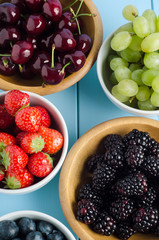 Five Fruit Types in Bowls from Above on Wood Plank Table