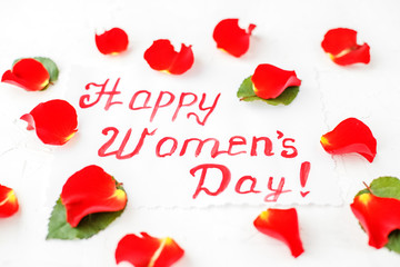 Background with greetings and red roses petals. Concept of Happy Women's Day.