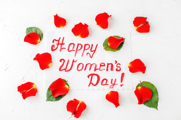 White background with greetings and petals of flowers. Concept of Happy Women's Day. Flat lay. Concept of Happy Women's Day.