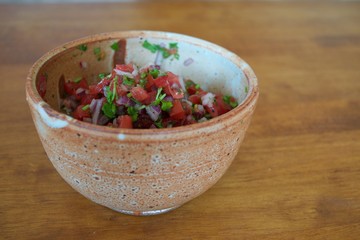 Homemade salsa fresca in bowl on wood table