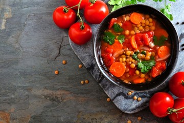 Homemade tomato, lentil soup, above view corner border with copy space on a dark slate background