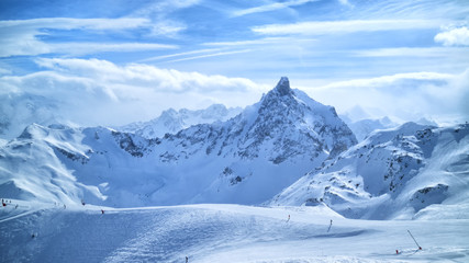 Alpine mountain peaks in clouds, ski slopes, off piste trails in winter sport resort of Courchevel, 3 Valleys, France . - obrazy, fototapety, plakaty