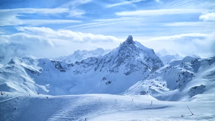Fototapeten Alpine mountain peaks in clouds, ski slopes, off piste trails in winter sport resort of Courchevel, 3 Valleys, France . © Yols