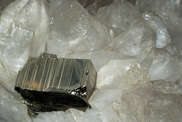 large rectangular pyrite crystal among quartz crystals closeup..