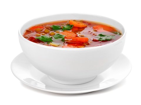 Homemade tomato, lentil soup in a white bowl with saucer. Side view isolated on a white background.