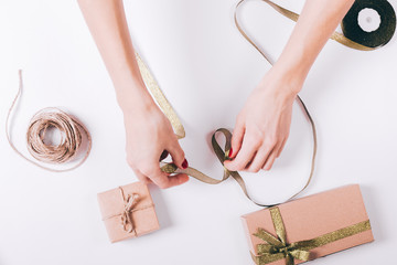 Female hands wrapping gifts on a white table