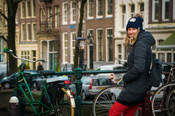 Obraz premium Tourist in Amsterdam - woman in her 30s waiting beside bicycles on a bridge in Amsterdam