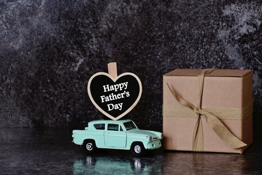 Father's day composition on the dark background. Gift box and car with heart. Father's day concept