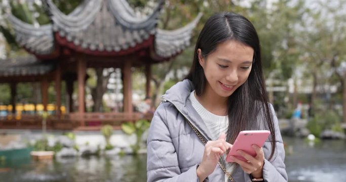 Woman use of smart phone in chinese garden