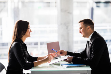 Businesspeople sitting at a table and signing a contract at office