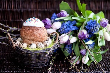 a bunch of spring flowers in lilac tones, and a cup of coffee with Easter bread and eggs, Easter