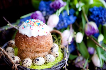 a bunch of spring flowers in lilac tones, and a cup of coffee with Easter bread and eggs, Easter