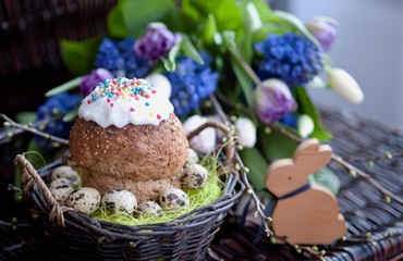 a bunch of spring flowers in lilac tones, and a cup of coffee with Easter bread and eggs, Easter