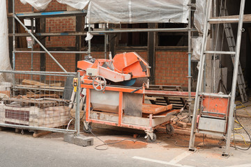 Eine Tischkreissäge zum Zuschneiden für Ziegelsteine steht vor einer Hausbaustelle