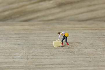 Obraz premium miniature model women bend dow to hold heavy suitcase luggage and bag on wooden background 