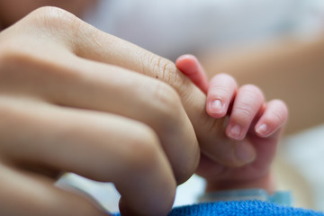 Close-up of a newborns finger touching mothers hand.Selective focus.