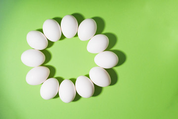 White chicken easter eggs laid out in an circle on green background